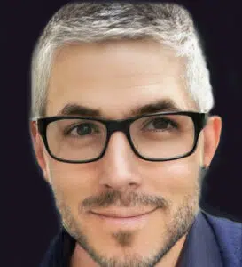 A man with white hair and glasses is smiling.