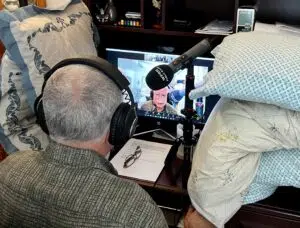 A man with headphones on sitting in front of a tv.