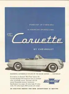 A white car is parked in front of the words " chevrolet corvette ".