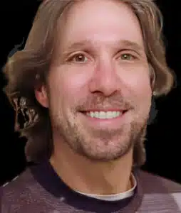 A man with long hair and beard smiling for the camera.