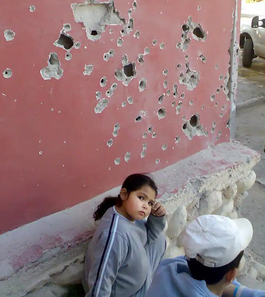 A girl sitting on the ground next to a wall.