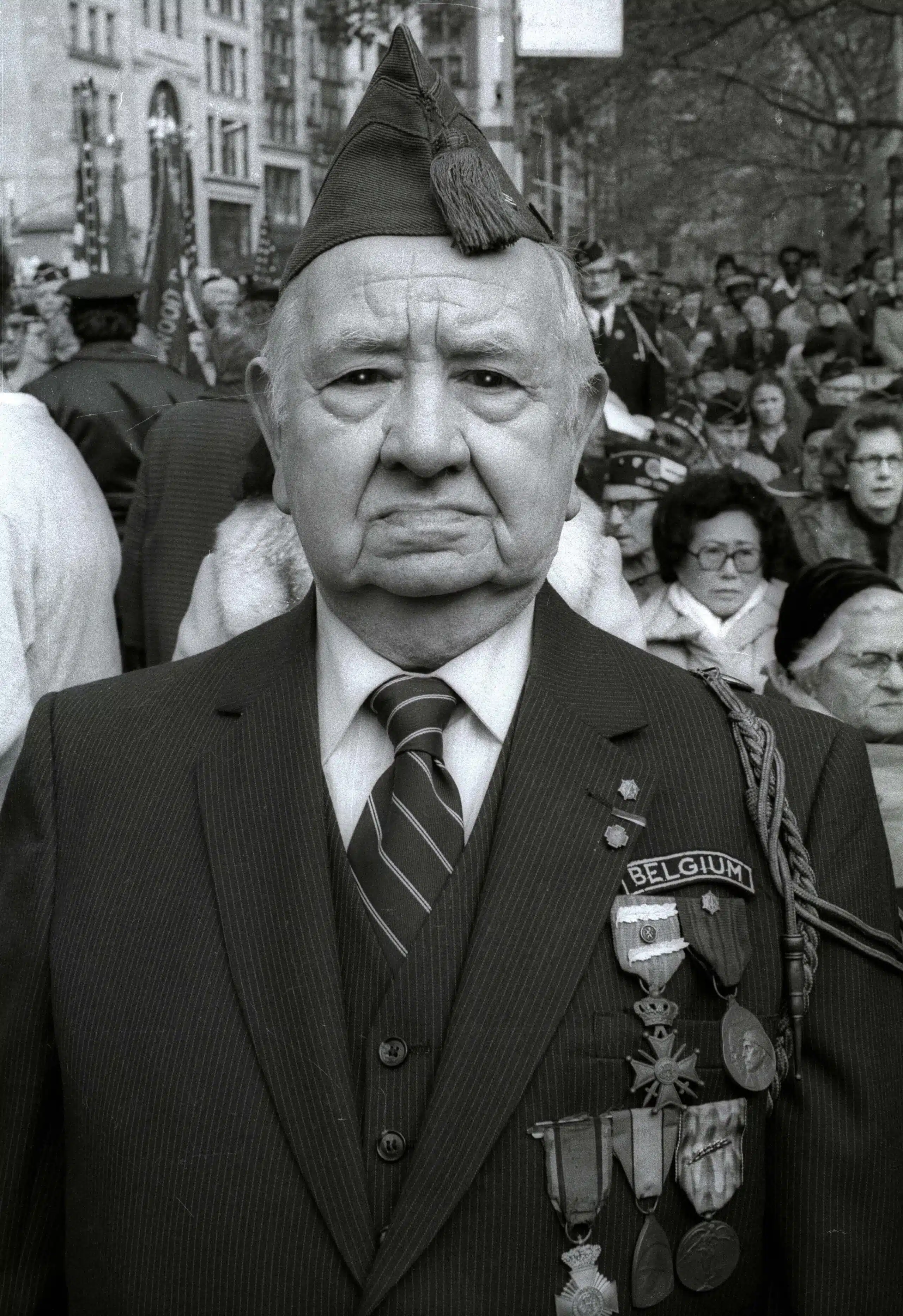 A man in suit and tie standing next to crowd.