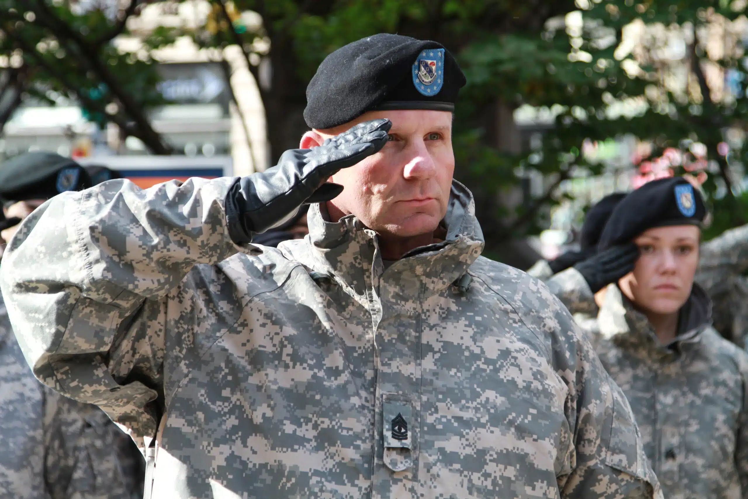 A man in military uniform saluting with his hand raised.