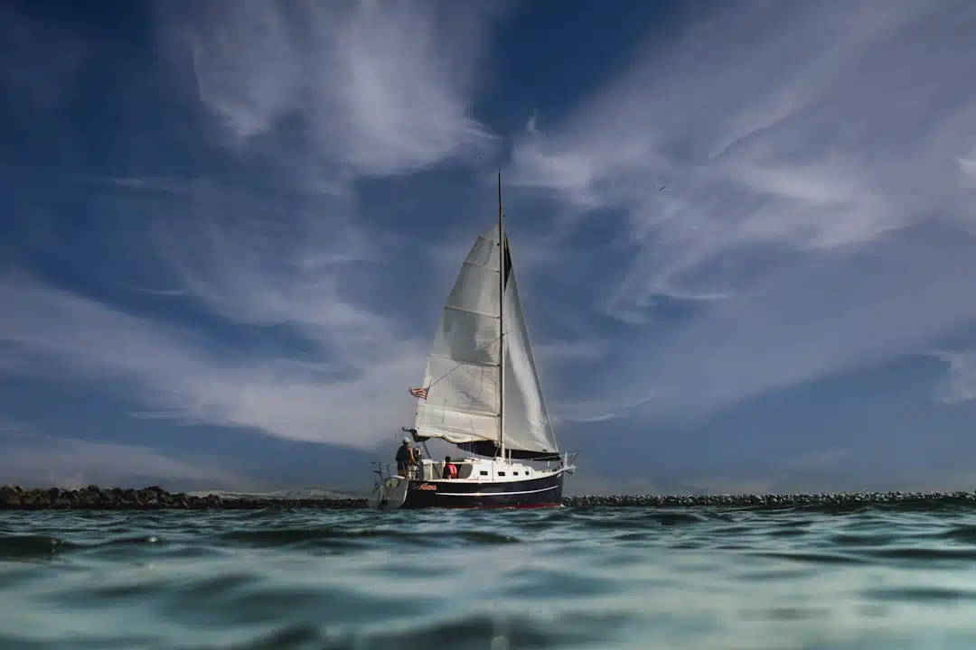 A sailboat in the ocean under a cloudy sky.