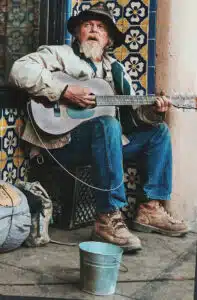 A man sitting on the ground playing an instrument.