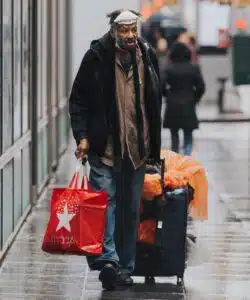 A man walking down the street with luggage.
