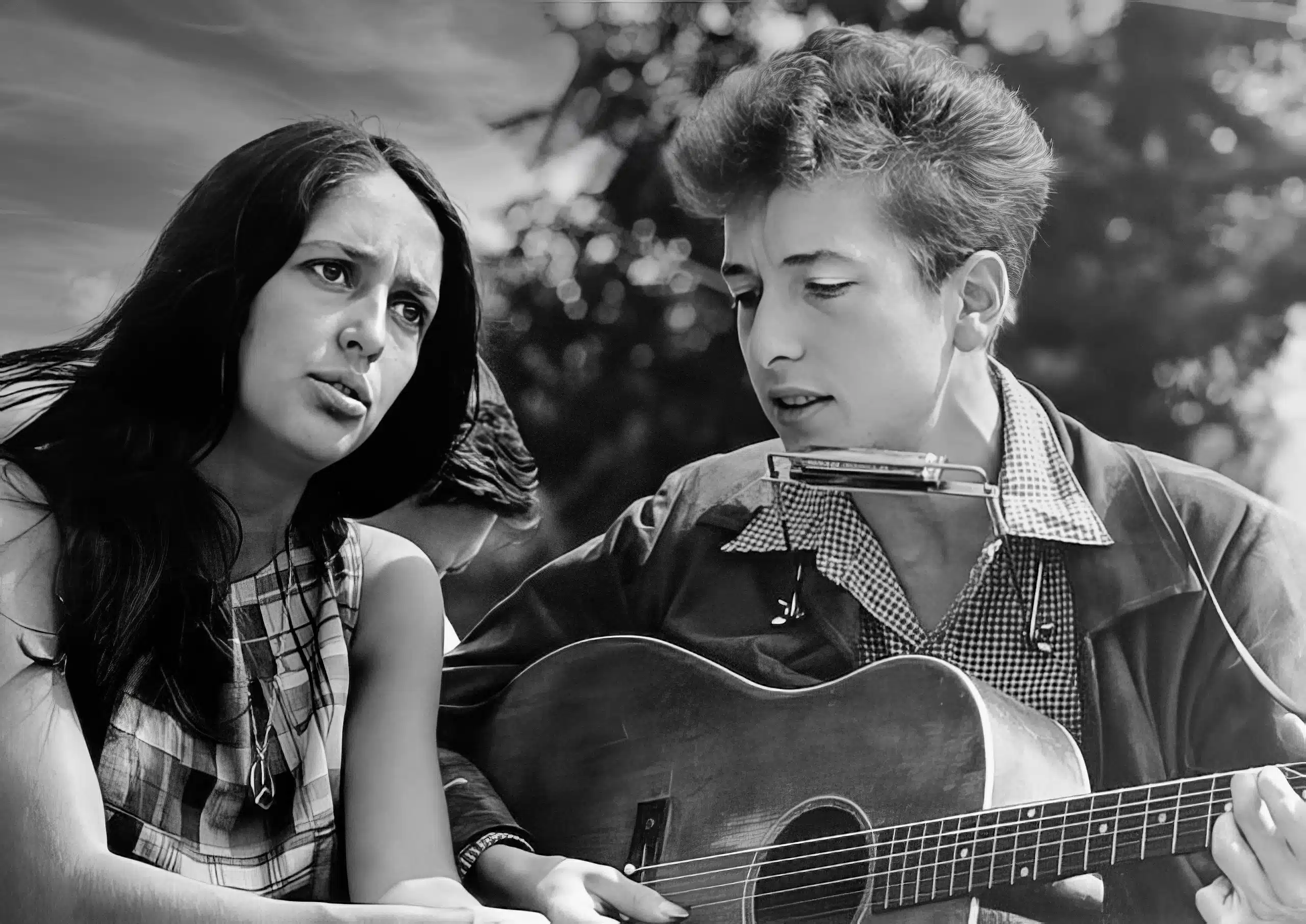 A young man playing an acoustic guitar next to a woman.