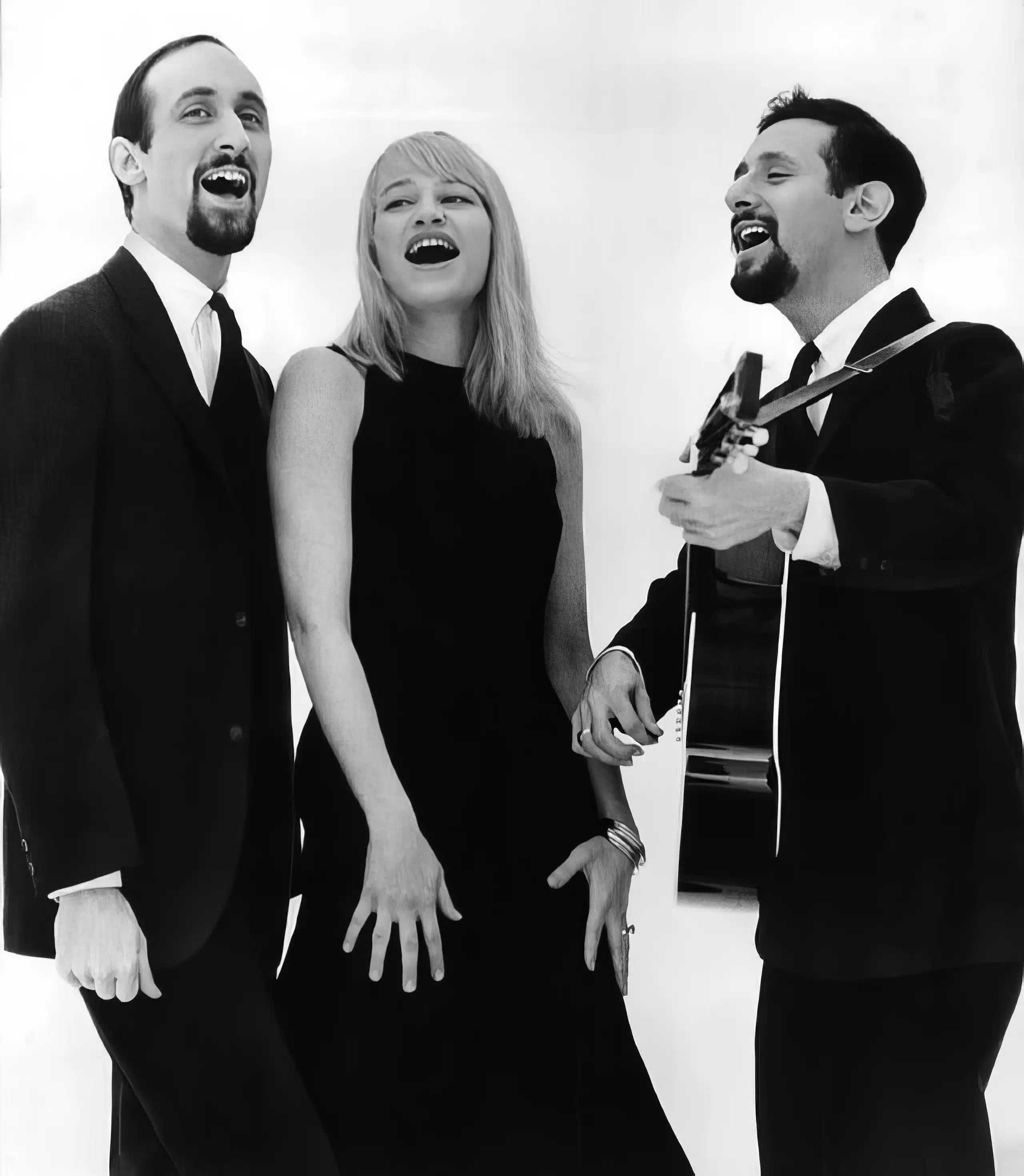 A group of people singing together in front of a white background.