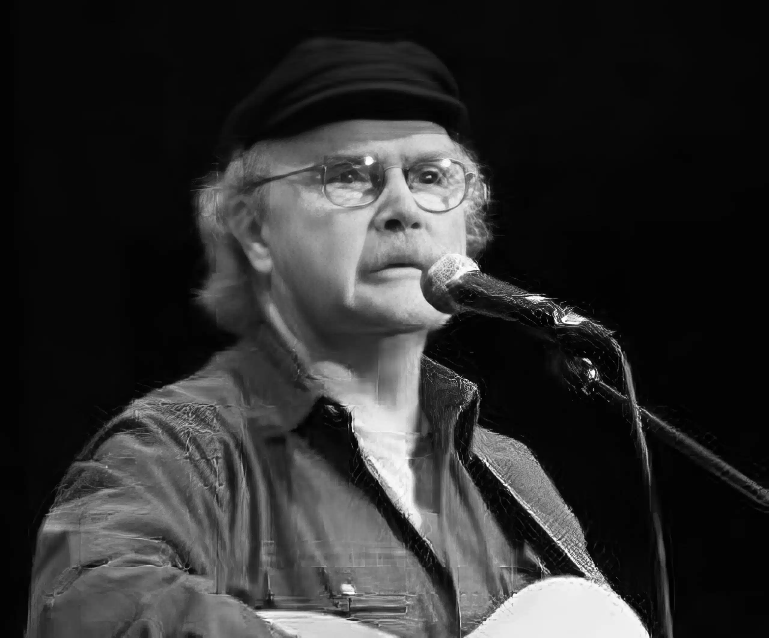 A man with glasses and a hat is holding a guitar