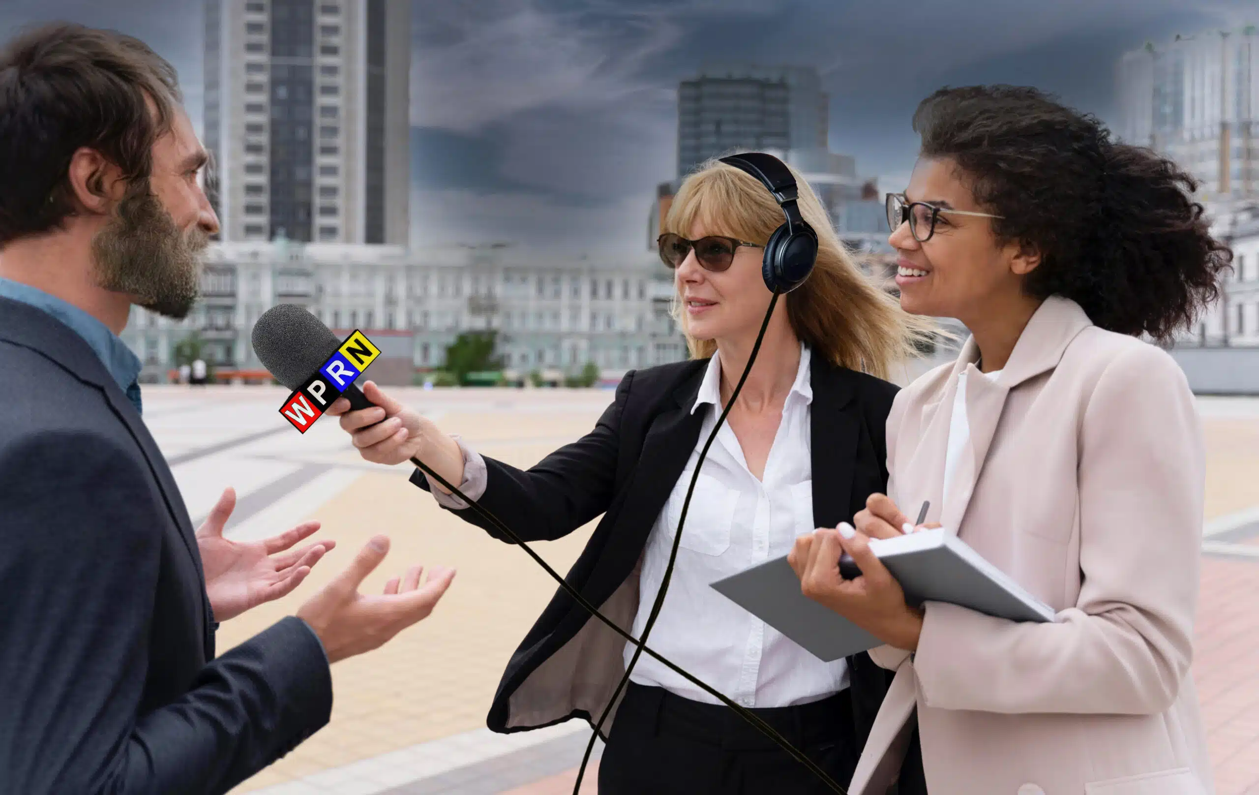 Two women are interviewing a man on the beach.